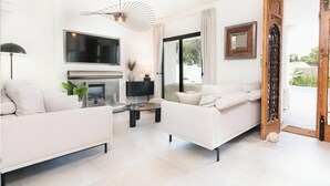 A modern living room with a fireplace, two sofas, a TV, and a dining area. - Villa Milana • Sea views & Beach vibes (Moraira)