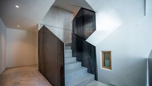 Eine moderne Treppe mit geometrischem Design, einem kleinen Fenster und einer schlichten Wand.