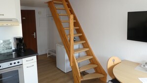 A kitchen with a built-in oven, a coffee maker, and a wooden staircase leading to a loft area. - Idyllic location on the Wennsee and 10 min walk to the beach with beautiful garden. (Scharbeutz)
