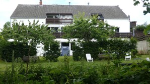 A two-story house with a sloped roof, a front door, and a small porch area. - Idyllic location on the Wennsee and 10 min walk to the beach with beautiful garden. (Scharbeutz)
