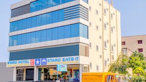 A hotel with a modern facade, featuring a restaurant named "STARO EATS" and a sign indicating "HAPPY FOOD + HAPPY PRICE". - Staro Hotel - Hotel In Vijayawada (Vijayawada)