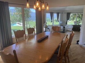 Enjoy meals in this dining area with a large table and six chairs, surrounded by a view of the lush garden and distant mountains.