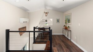 Un interior moderno con una escalera, piso de madera, un ventilador de techo y una cabeza de venado montada.