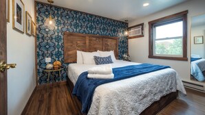 Een slaapkamer met een houten hoofdbord, een groot raam en behang met een patroon.
