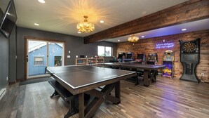 Een kamer met pingpongtafels, spelautomaten en een neonbord.