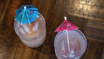 Two glasses of iced drinks with umbrellas on a wooden surface.
