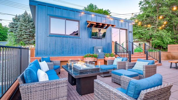 Een modern terras buiten met wicker meubels en een ingebouwde vuurplaats.