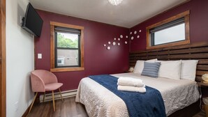 Ein Schlafzimmer mit einem Bett, einem Sessel, einem Fernseher und einem Fenster.