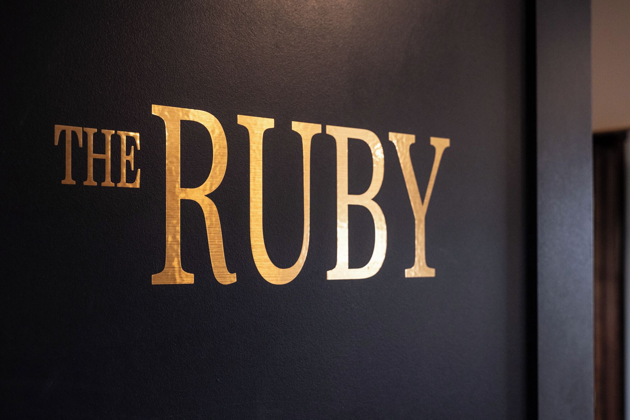 A wall with the text "THE RUBY" in large, gold letters.