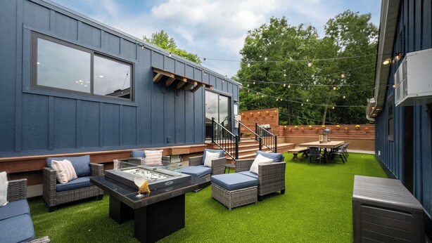 Eine moderne Außenpatio mit Kunstgras, Korbmöbeln und einer Grillgelegenheit.