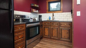 Eine Küche mit Holzschränken, einem Edelstahlkühlschrank und einem Fenster über der Spüle.