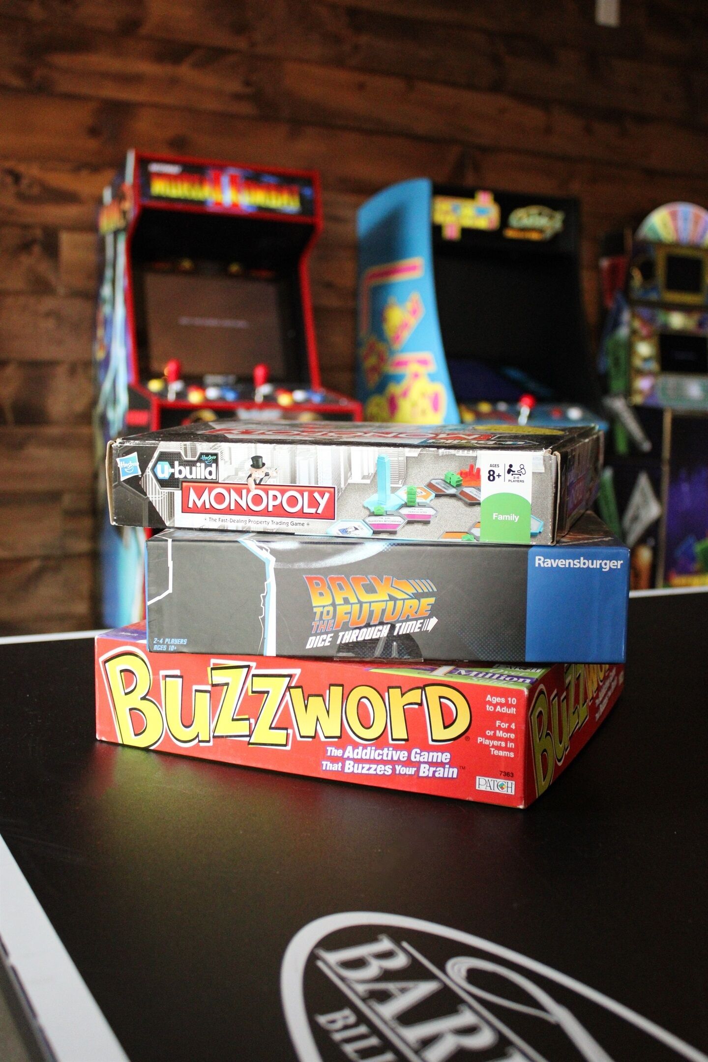A table with three board games: Monopoly, Buzzword, and Back to the Future.