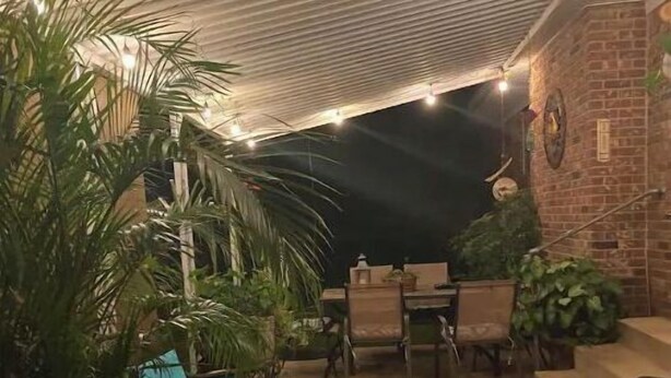 An outdoor patio area with a brick wall, a table with chairs, and several lounge chairs. - Robins Nest "The Best Nest In Town"  Newly Remodeled Master Bath. (Murfreesboro)