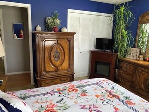 A bedroom with a floral bedspread, a wooden wardrobe, a television, and a mirror. - Robins Nest "The Best Nest In Town"  Newly Remodeled Master Bath. (Murfreesboro)