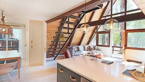 Ein Loft-Zimmer mit großem Fenster, einer Treppe und einem Essbereich.