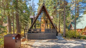 Eine Holzhütte mit einer Holzdiele und einer Glasfront, umgeben von Bäumen.
