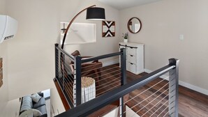 Un interior moderno con una escalera, un armario blanco y un espejo redondo.