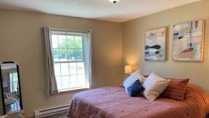 A bedroom with a large bed, a chair, a window, and two paintings on the wall. - Sweet Escape, next to C-I bike/snowmobile trail. (Crosby)