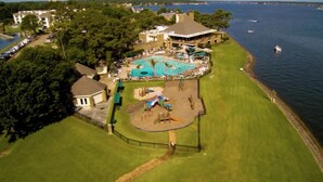 Eine Luftaufnahme eines Resorts mit Schwimmbad, Kinderspielplatz und Bootsanleger.