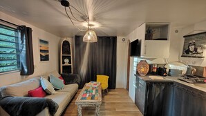 Ein gemütliches Wohnzimmer mit einer Couch, einem kleinen Tisch und einer Küchenzeile mit Spüle und Arbeitsfläche.