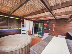 A covered outdoor area with a hot tub, wooden deck, and a glass door leading to a room. - nugget! Ocean view studio with private Jacuzzi in an exceptional tropical garden  (Les Avirons)