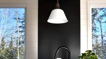 A modern kitchen with a black countertop, a stainless steel sink, and two pendant lights.