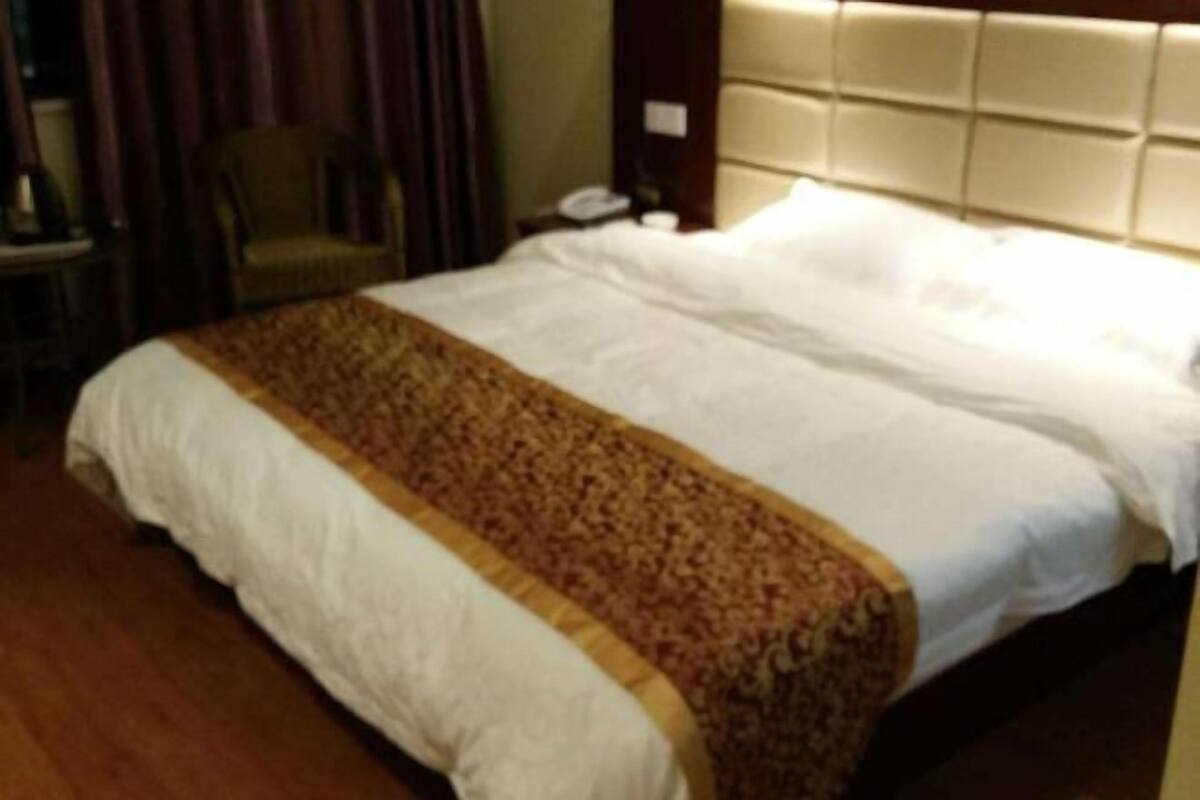 Een hotelkamer met een groot bed, hoofdeinde, een stoel en nachtkastje.