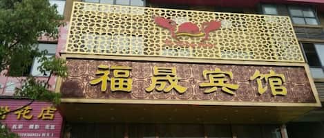 Un edificio con un letrero llamativo que dice '福晟客館' (Fukshin Guesthouse).