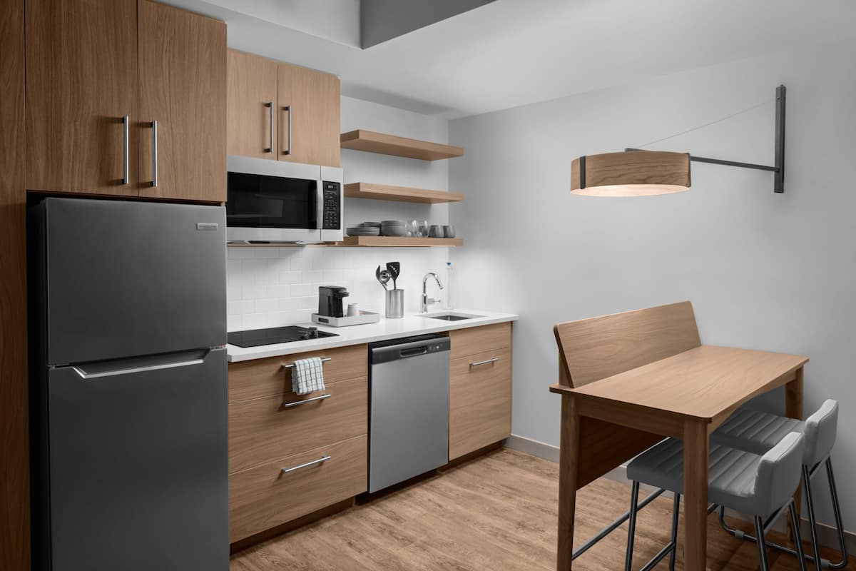 Eine moderne Küche mit Kühlschrank, Mikrowelle, Spüle und Holzschränken.