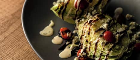 A plate with stuffed cabbage rolls, tomatoes, and crumbled cheese, drizzled with sauce.