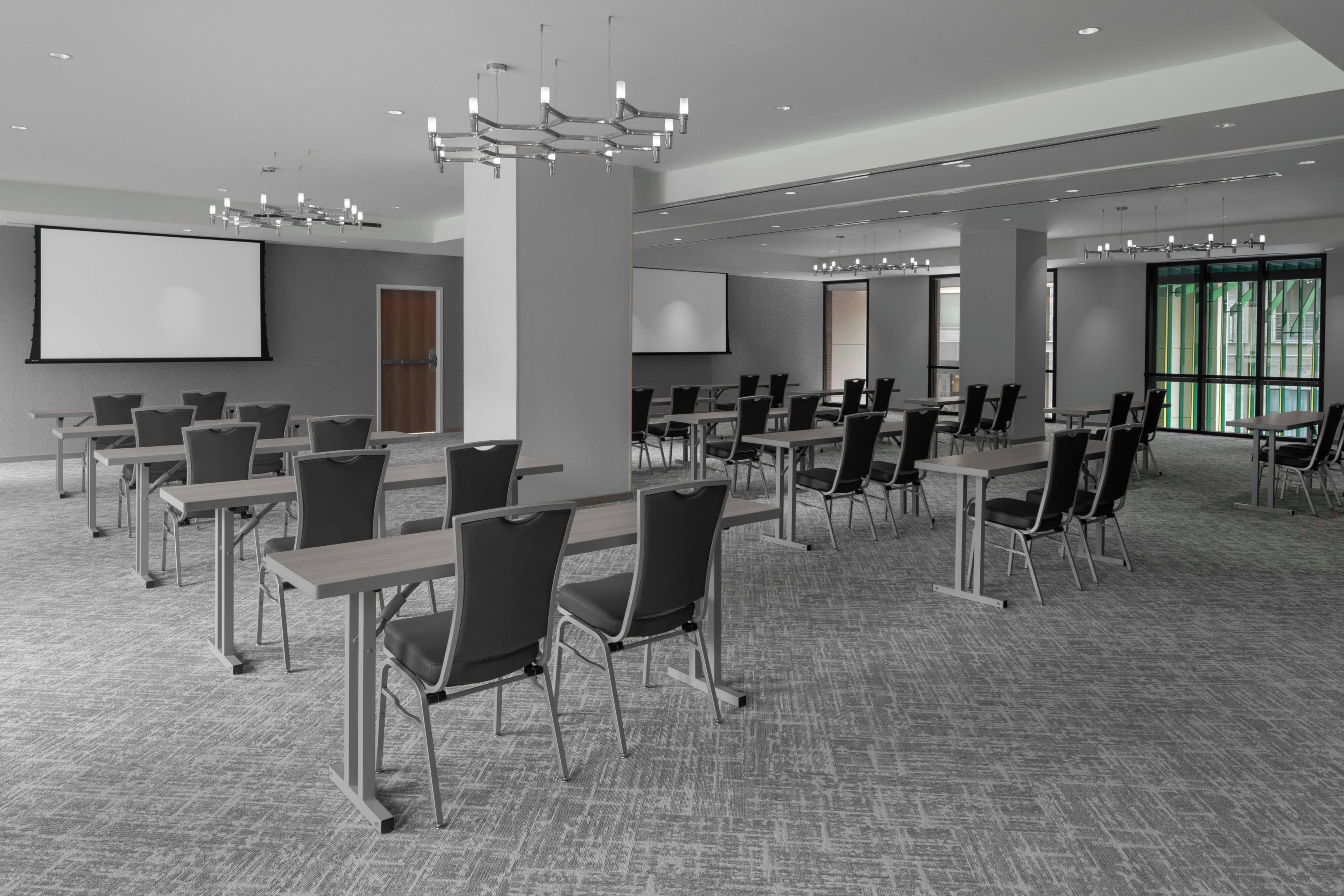 Une salle de conférence équipée de plusieurs tables et chaises, d’un grand écran et d’un projecteur.