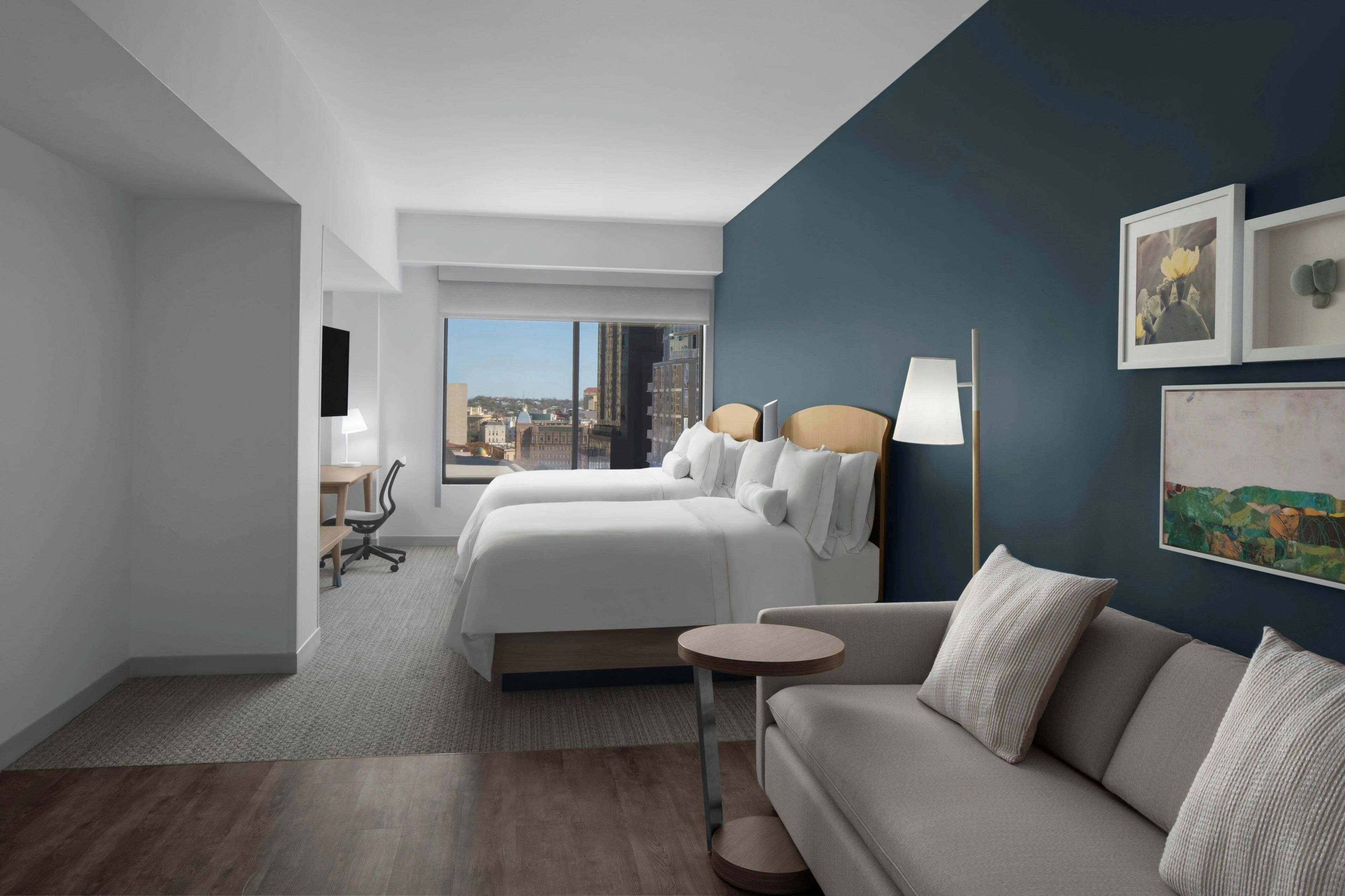 Una camera d'hotel con un letto grande, un divano, una scrivania e vista sulla città.