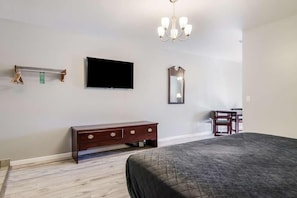 A bedroom with a bed, a dresser, a television, a mirror, and a chandelier. - Relax and Unwind in GuestHouse Montesano! Free Parking, Pet-friendly Property (Montesano)