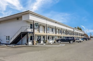 A multi-story motel with a covered entrance and a staircase leading to the parking area. - Relax and Unwind in GuestHouse Montesano! Free Parking, Pet-friendly Property (Montesano)