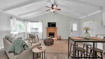 Cozy living space with a central fireplace, dining table, and kitchen area featuring a refrigerator and sink.