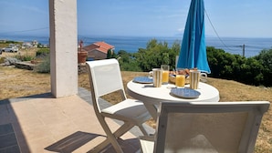 Een terras met een ontbijttafel, met uitzicht op een prachtig zeegezicht.