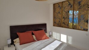 Een slaapkamer met een bed, nachtkastjes, een decoratief wandpaneel en een hanglamp.