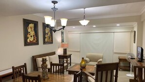 A dining area with a wooden table and chairs, a chandelier, and artwork on the walls. - Apartamento en el centro de la ciudad (La Romana)