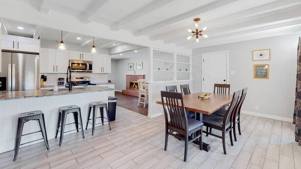 A modern kitchen with white cabinetry, a central island with stools, and pendant lighting. - Comfortable Family Home in Beautiful Neighborhood (Denver)