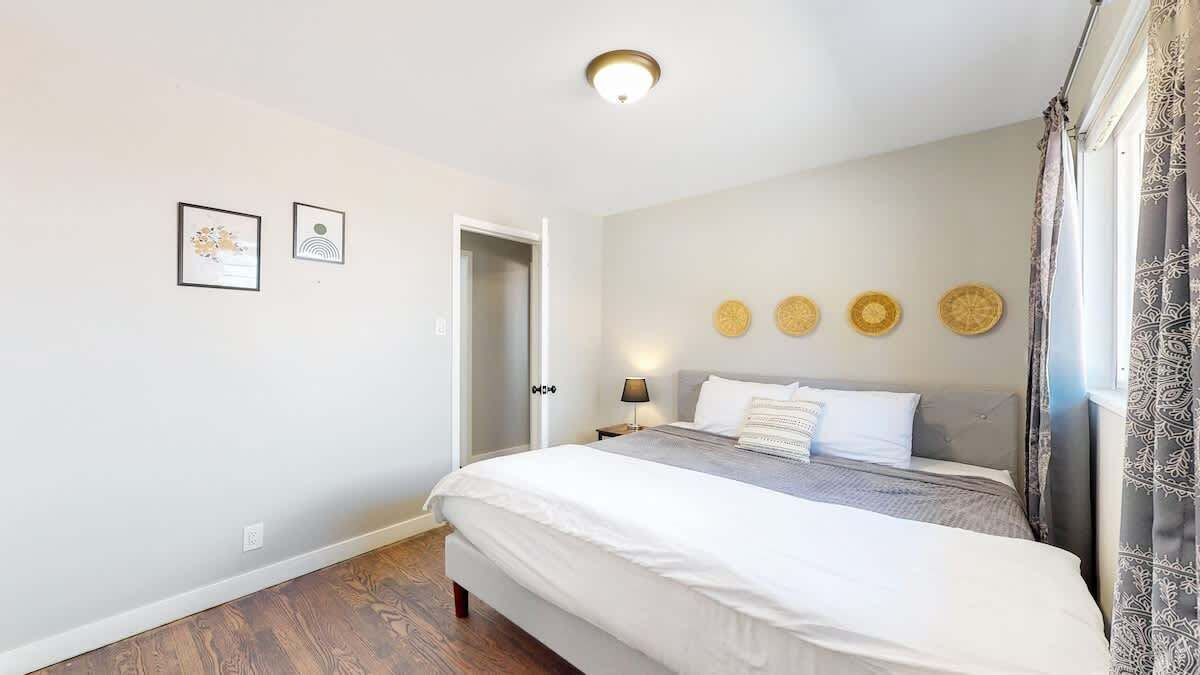 A bedroom with a bed, a nightstand, a wall-mounted lamp, and a door.