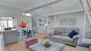 A modern living room with a grey sofa, a coffee table, and a dining area with chairs and a table. - The Perros house - PERROS GUIREC (PERROS GUIREC)