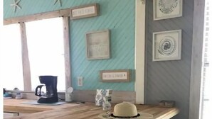 Cozinha com ilha de madeira, banquetas, cafeteira e estrelas-do-mar decorativas.