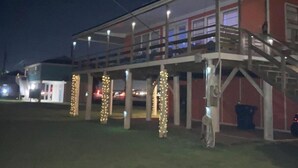 Um edifício com área externa coberta, colunas iluminadas e uma pessoa perto da entrada.