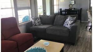 Sala de estar com sofá cinza, poltrona vermelha e mesa de madeira com uma tigela.