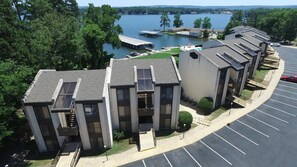 Een modern appartementencomplex met een parkeerplaats en uitzicht op een meer.