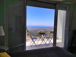 Relax on the balcony with a morning view of lush greenery and a distant horizon.
