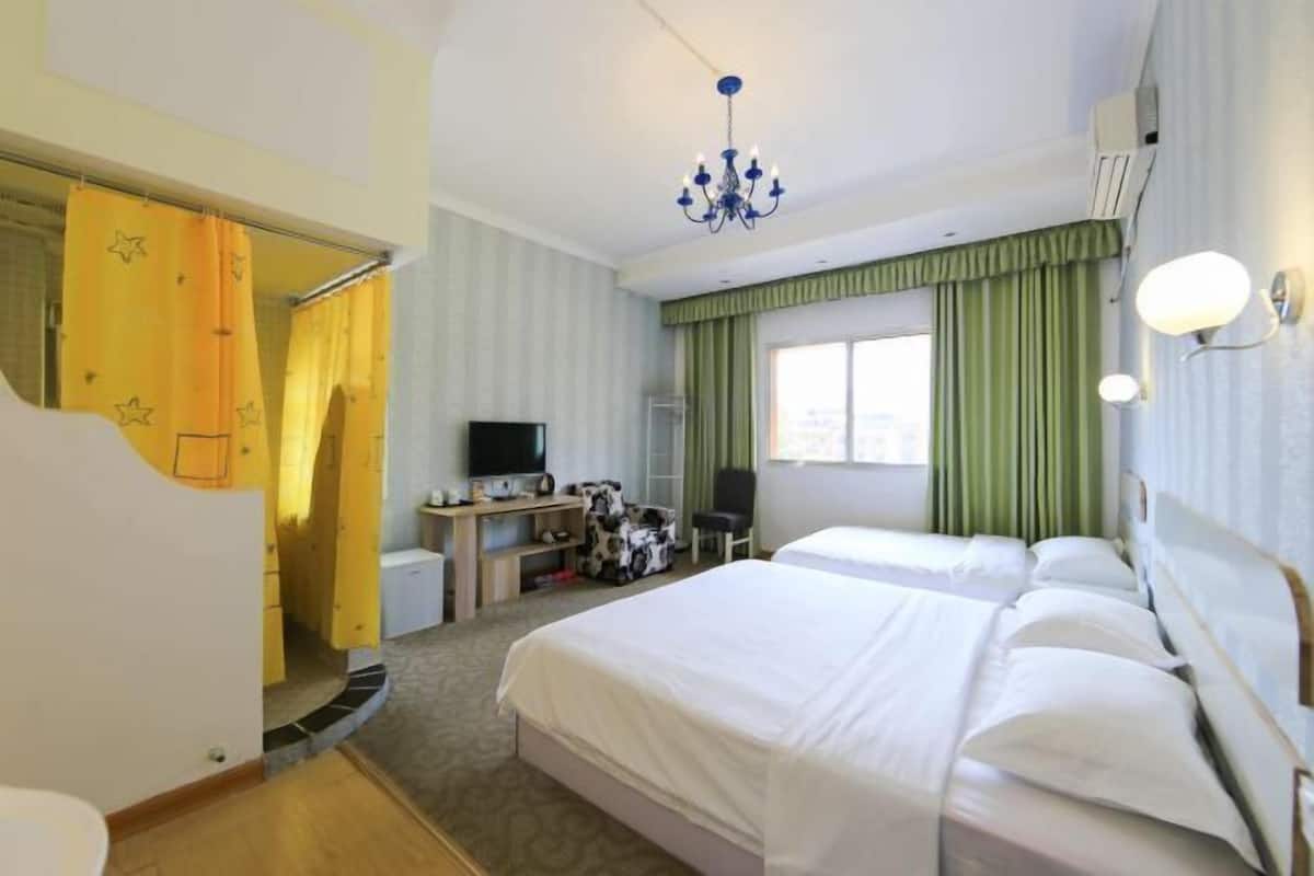 Une chambre d’hôtel avec deux lits, un bureau avec un ordinateur, une télévision et un lustre.