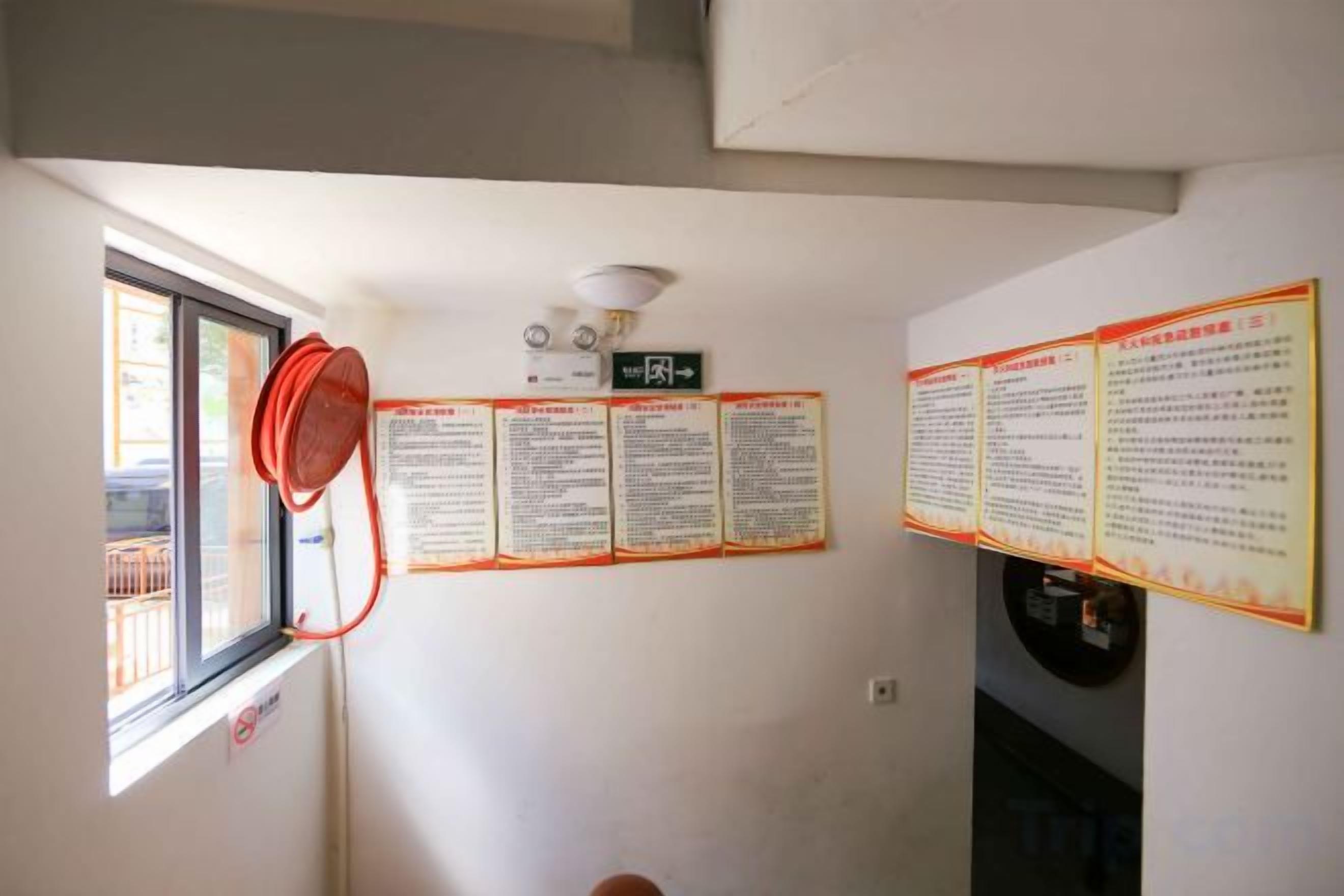 A room with a window, a ceiling fan, and multiple informational posters on the wall.