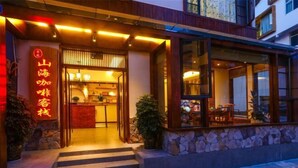 Ein Hotel Eingang mit traditionellem Design, mit einer Holzfassade, einem Steinunterbau und einem Schild mit chinesischen Schriftzeichen.