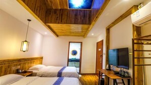 Ein Zimmer mit zwei Betten, einem Fernseher, einem Schreibtisch mit Computer und einem Dachfenster.